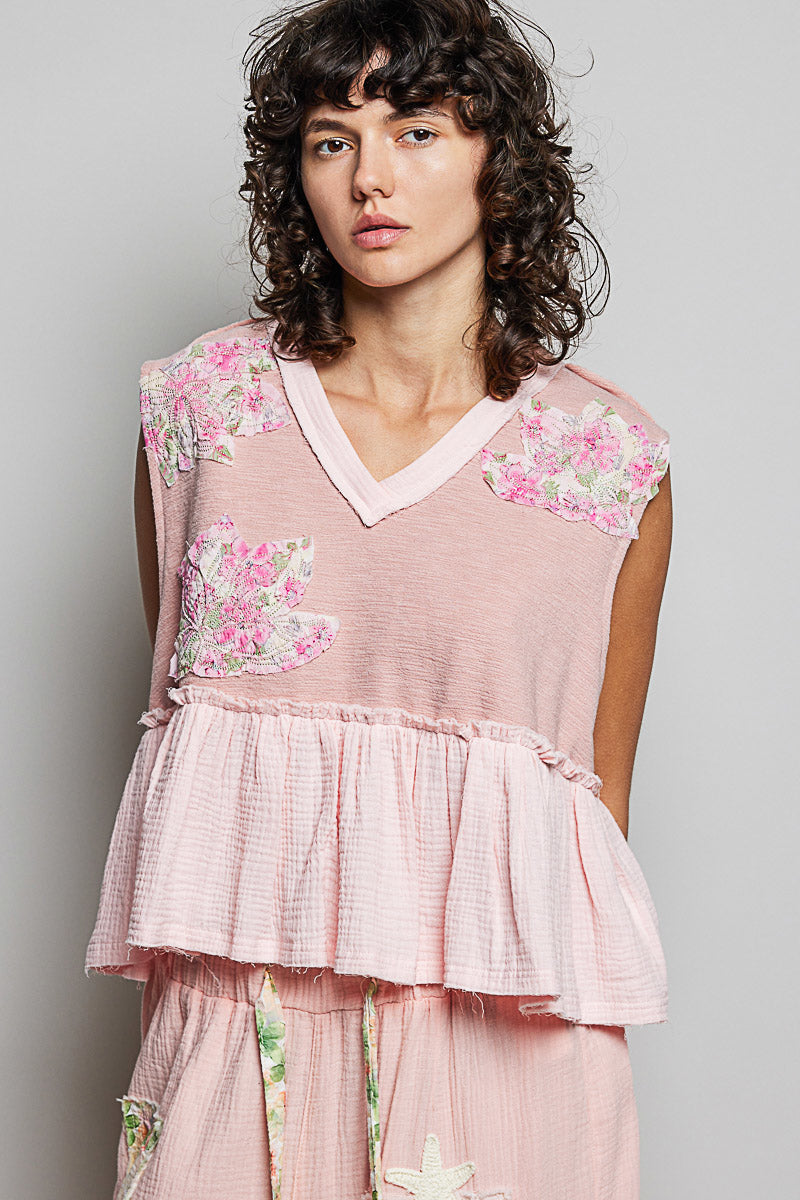 Powder pink sleeveless top with V-neck and tiered ruffle hem with floral patches