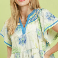 Floral babydoll dress close-up, blue contrast trim neckline and tiered bodice
