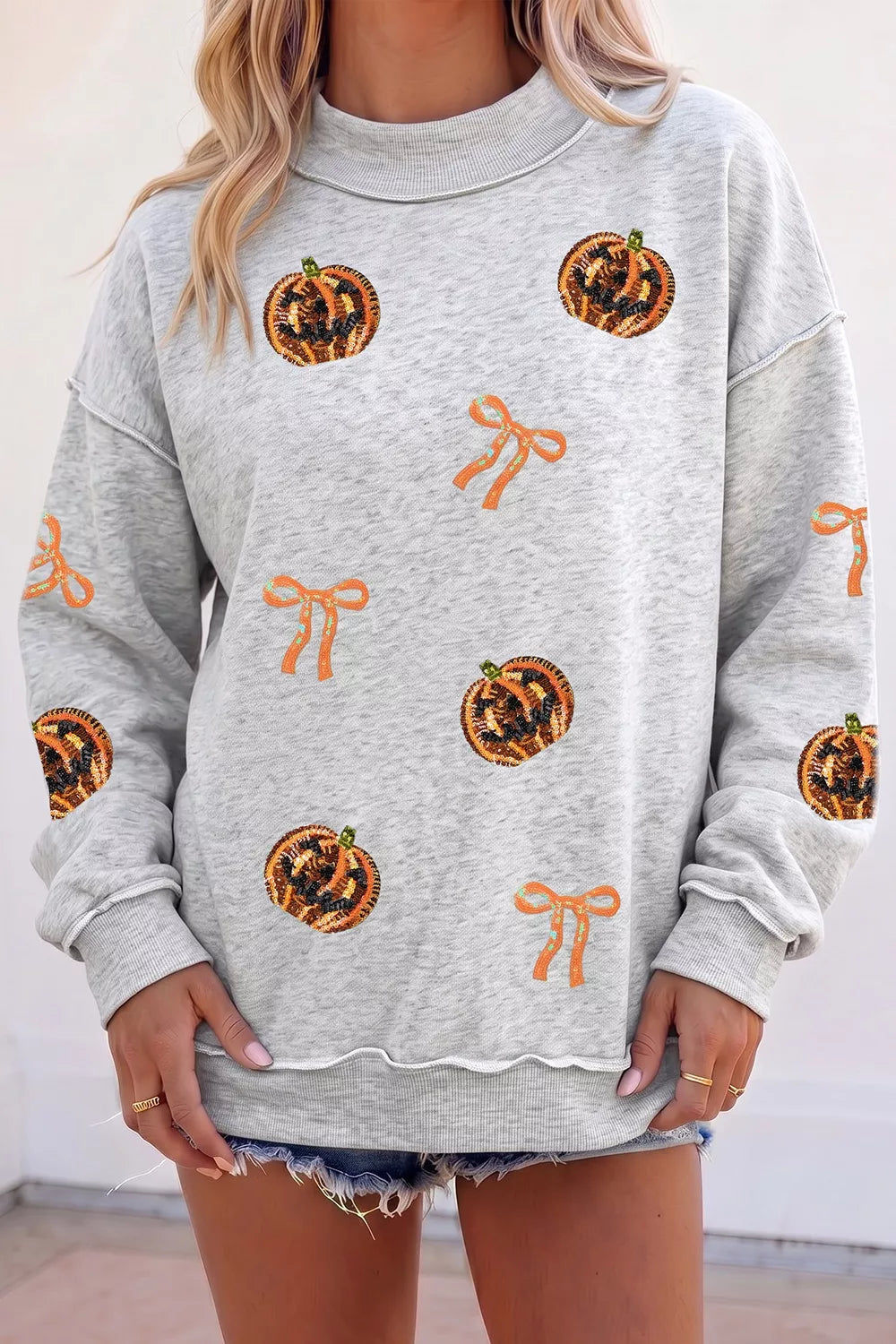 Light gray Halloween sweatshirt with orange pumpkin face and bow motifs, long sleeves