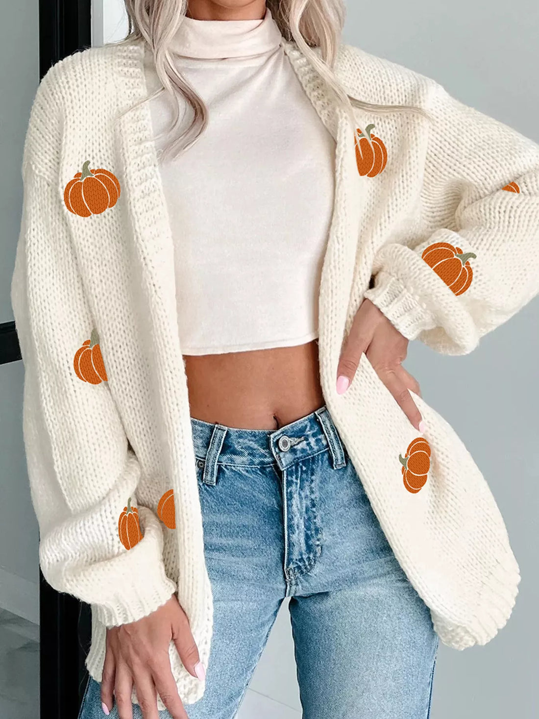 White knit cardigan with pumpkin embroidery, open front, long sleeves and ribbed cuffs.