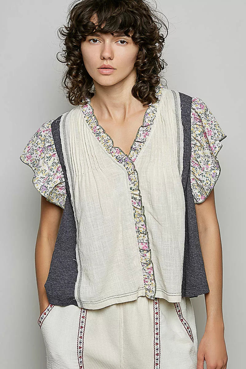 Cream V-neck blouse with floral ruffle sleeves, vertical trim, and button front