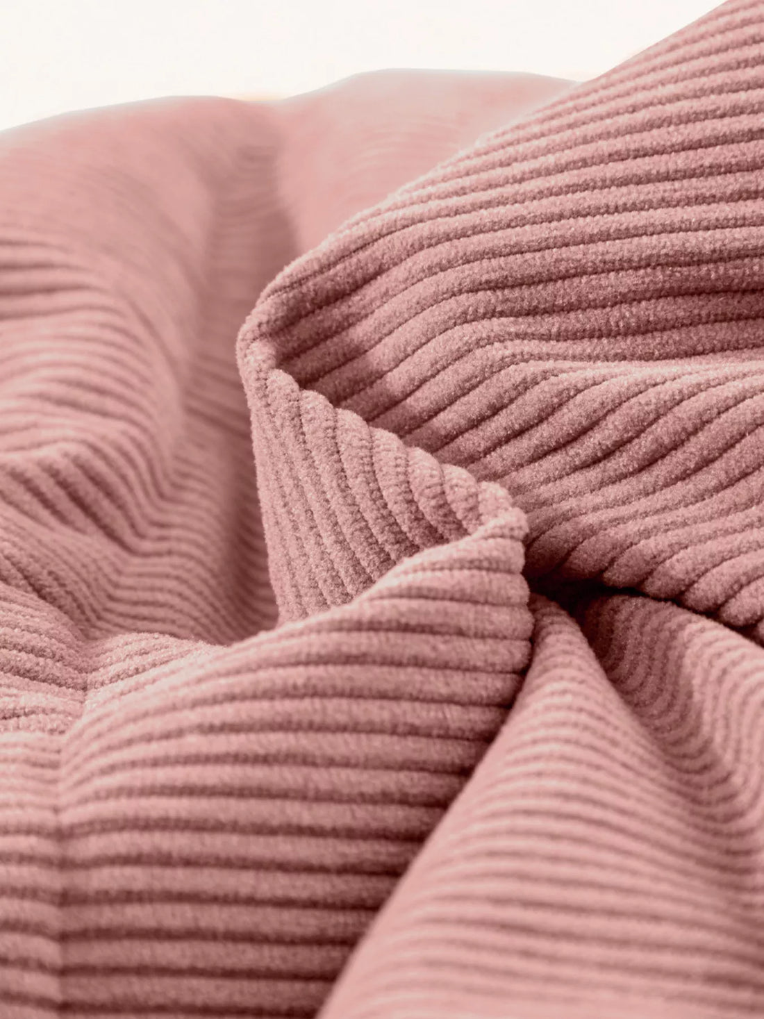 Dusty pink corduroy puffer fabric close-up with ribbed texture and stitched channel quilting.