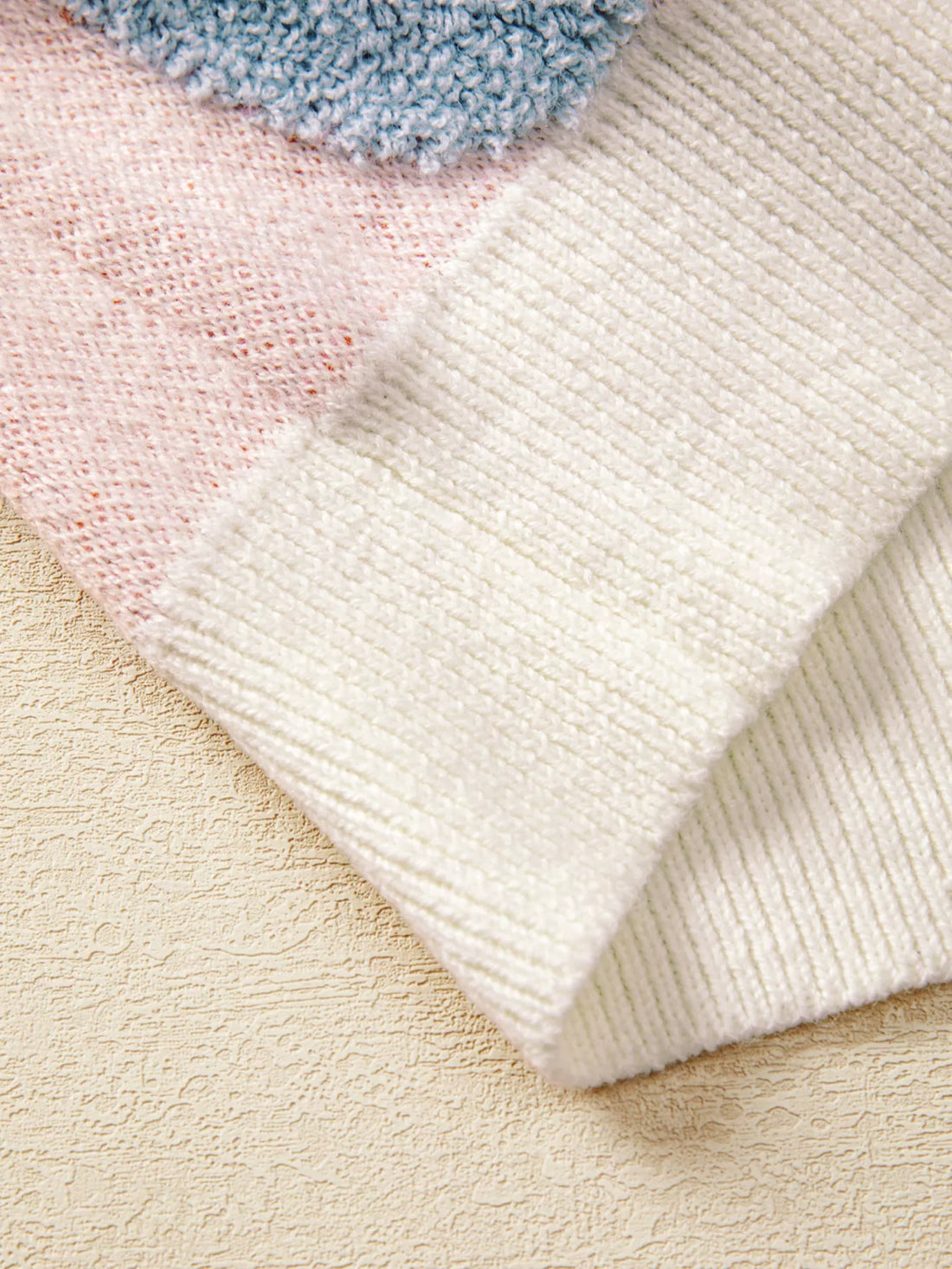 Ribbed knit hem and cuffs on dusty pink sweater in textured knit fabric