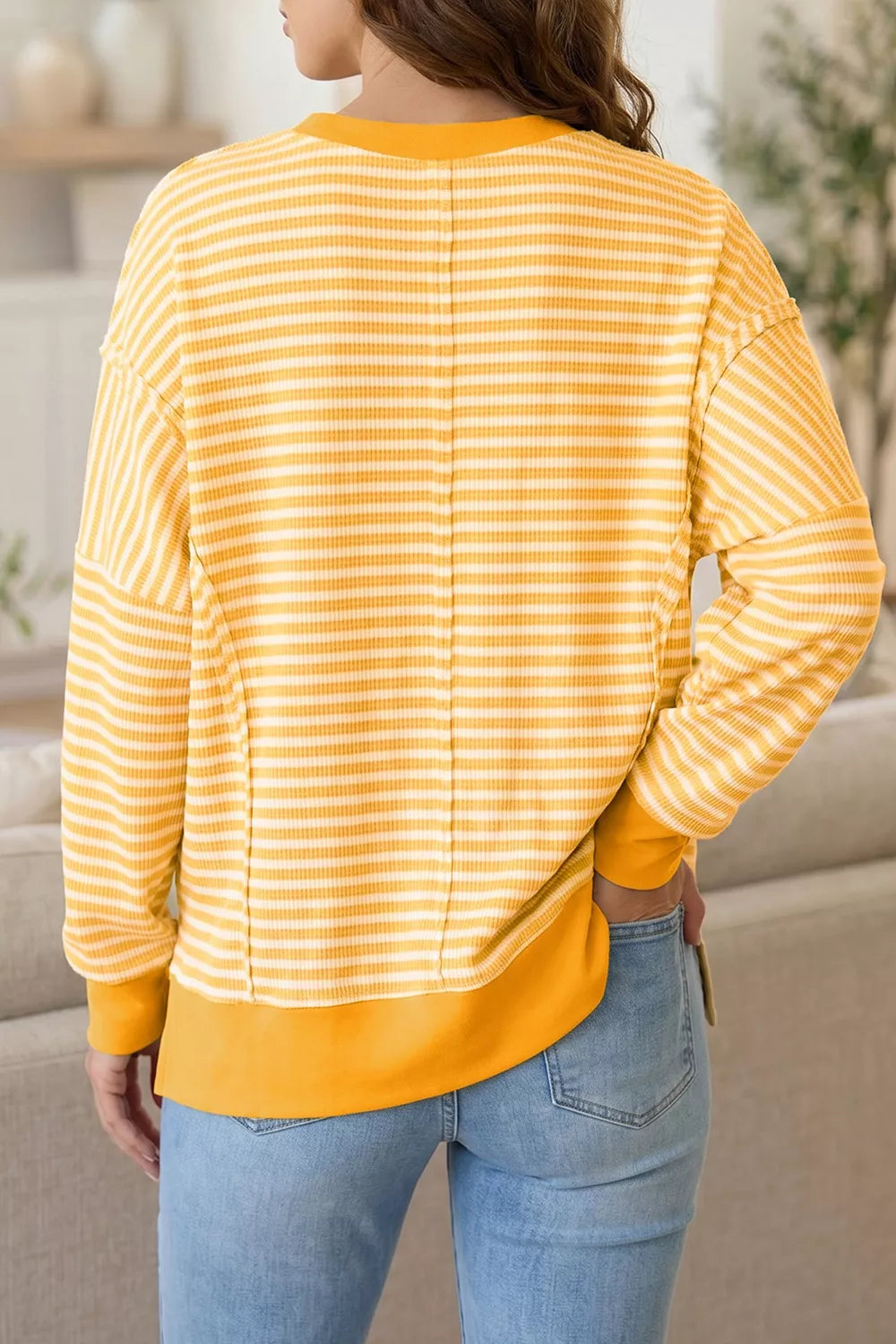Back view of gold-and-white striped long-sleeve Halloween top with split hem