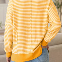 Back view of gold-and-white striped long-sleeve Halloween top with split hem