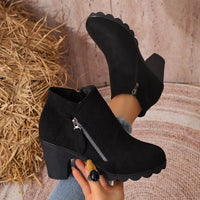 Black ankle boots with round toe, block heel, and side zipper on suede upper