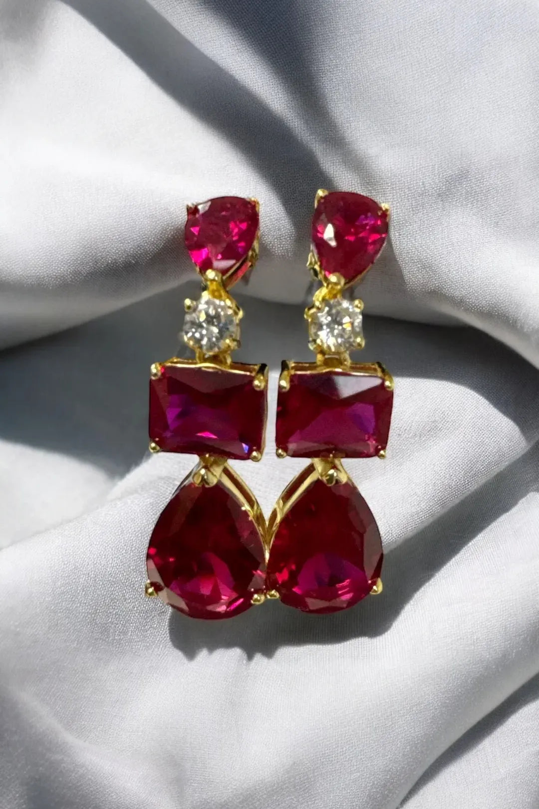 Gold drop earrings with ruby-red stones and small clear accent stones