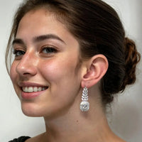 Silver-tone drop earrings with marquise clusters, worn on model’s ear