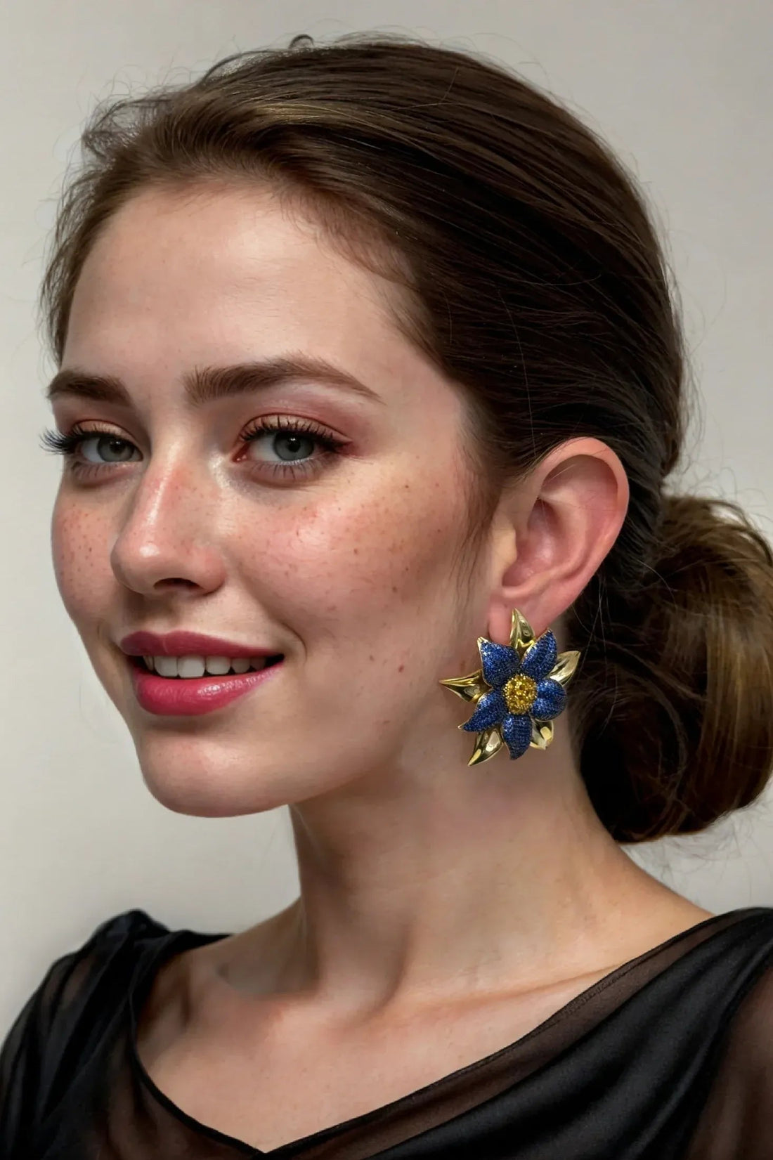 Blue daisy flower stud earrings with gold-tone backing, worn by a model.