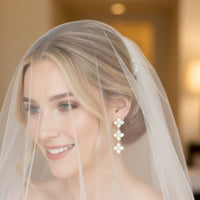 Gold mother-of-pearl clover triple-drop earrings on a bride under a veil