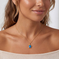 Gold pendant necklace with blue oval opal charm centered on a fine chain.
