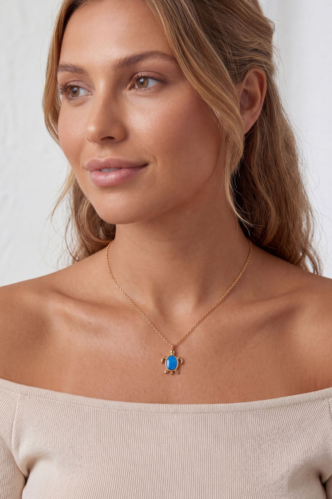 Gold pendant necklace with blue oval opal charm on a fine chain.