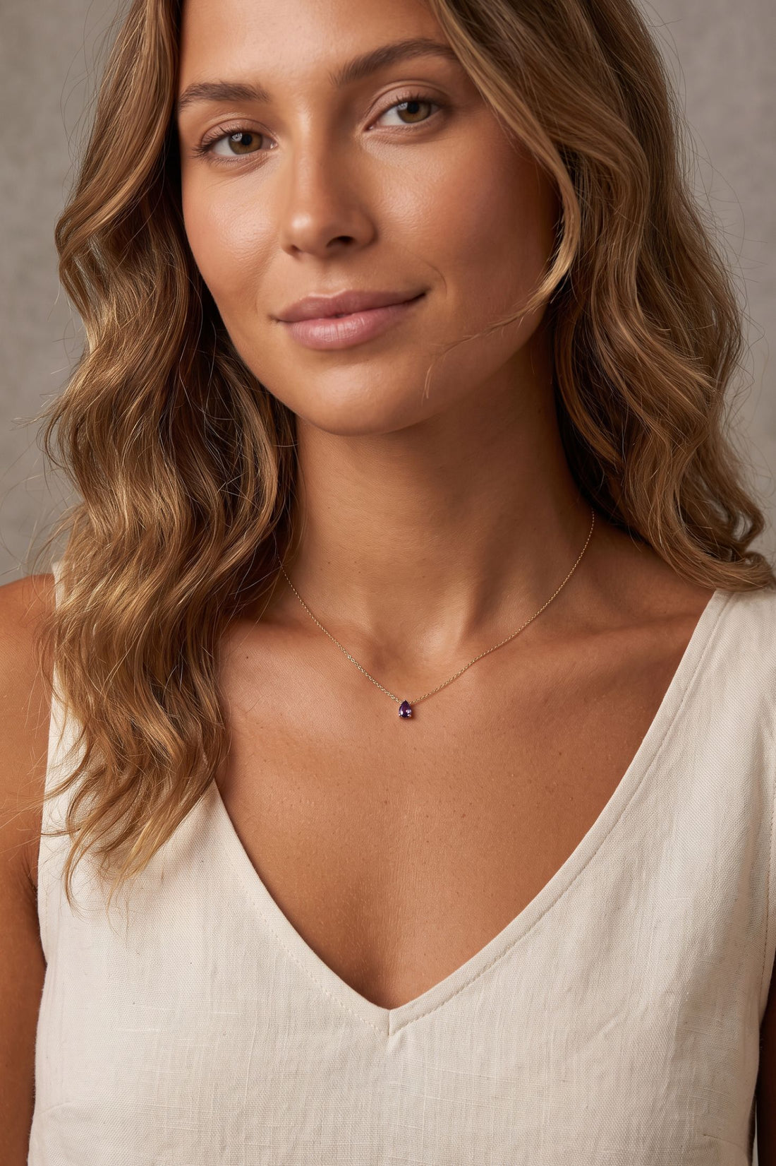 Gold teardrop gemstone pendant necklace worn on a neckline