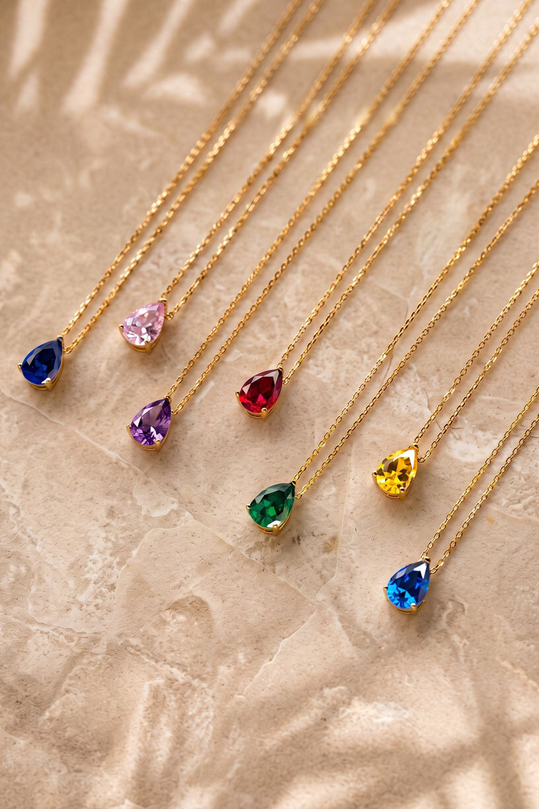 Gold teardrop necklace pendants with multicolor gemstones on chains
