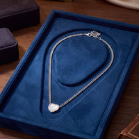Heart mother-of-pearl silver necklace lying in blue jewelry box on tabletop