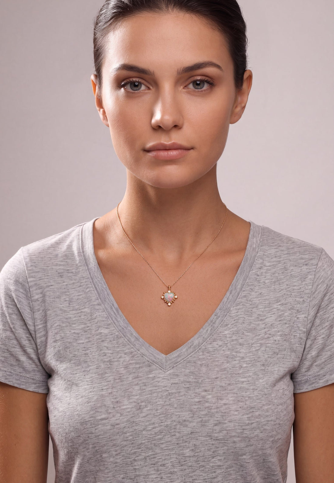 Gold heart pendant necklace with opal-like iridescent center on a model