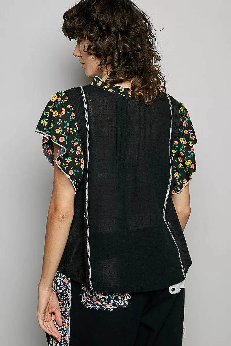 Black V-neck blouse with ruffle sleeves and floral print trim, back view