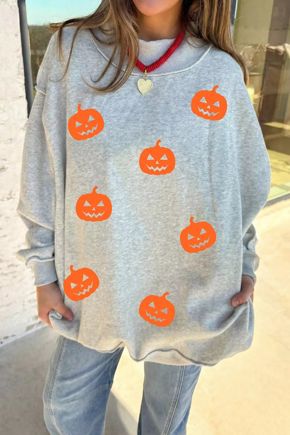 Light gray sweatshirt with orange pumpkin face motif all over