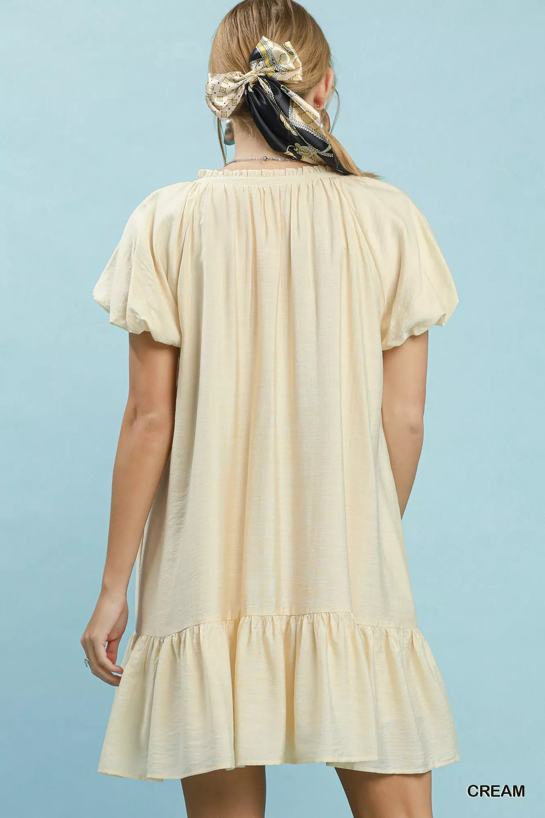 Cream mini shift dress, back view with gathered tiers and short sleeves.