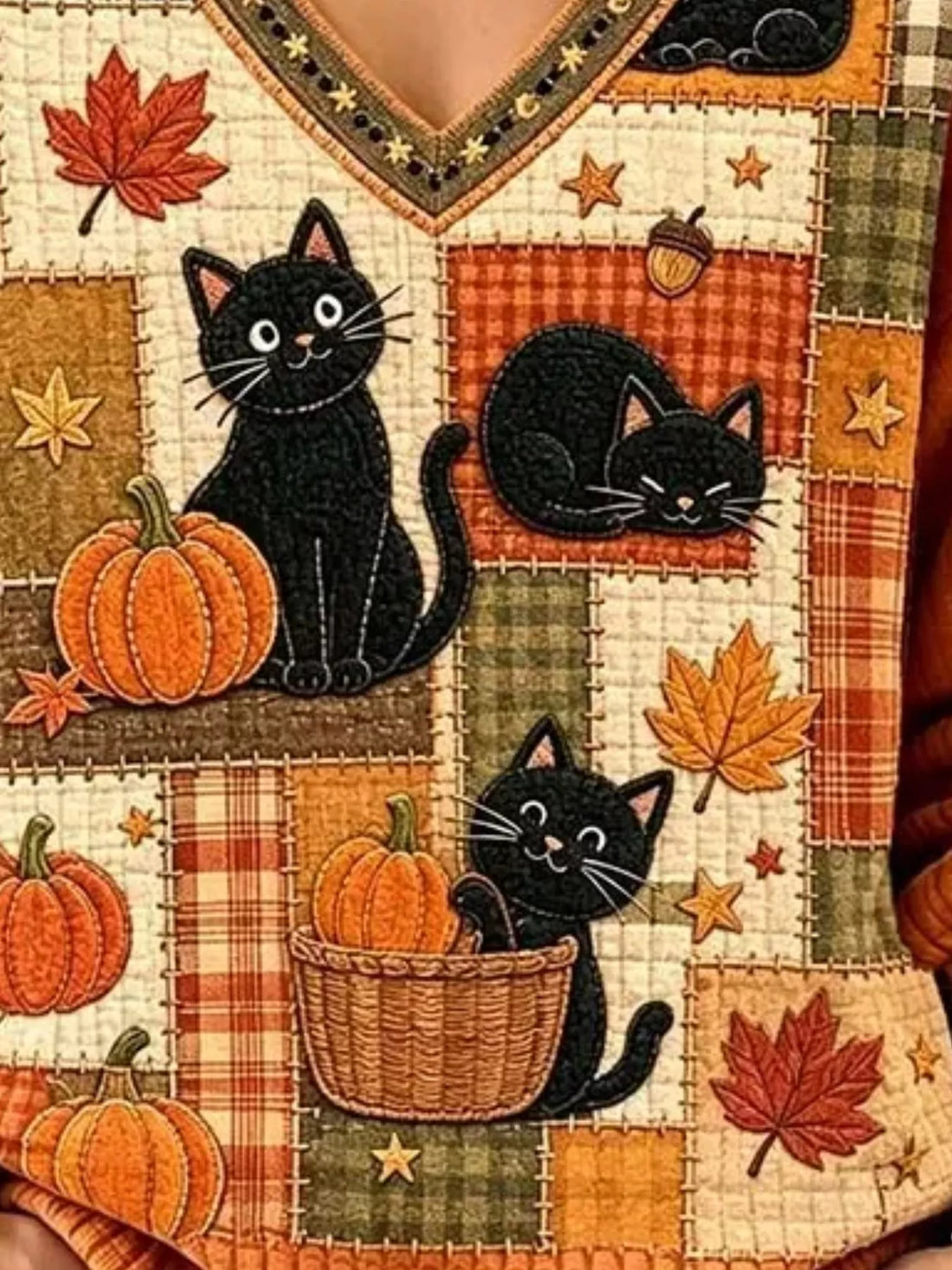 Orange V-neck sweater close-up: black cats with pumpkins, leaves, and patchwork blocks
