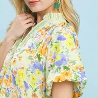 Green watercolor floral blouse close-up with embroidered V-neck and puff sleeve cuff