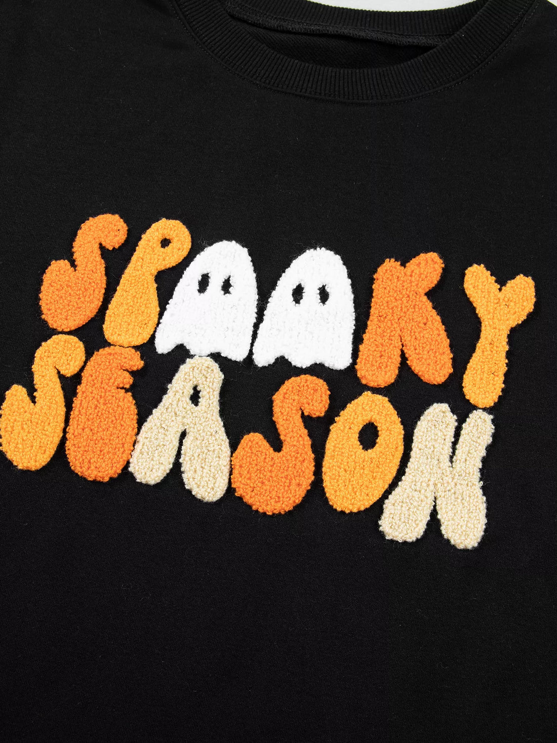 Close-up of embroidered “Spooky Season” graphic on black crewneck sweatshirt