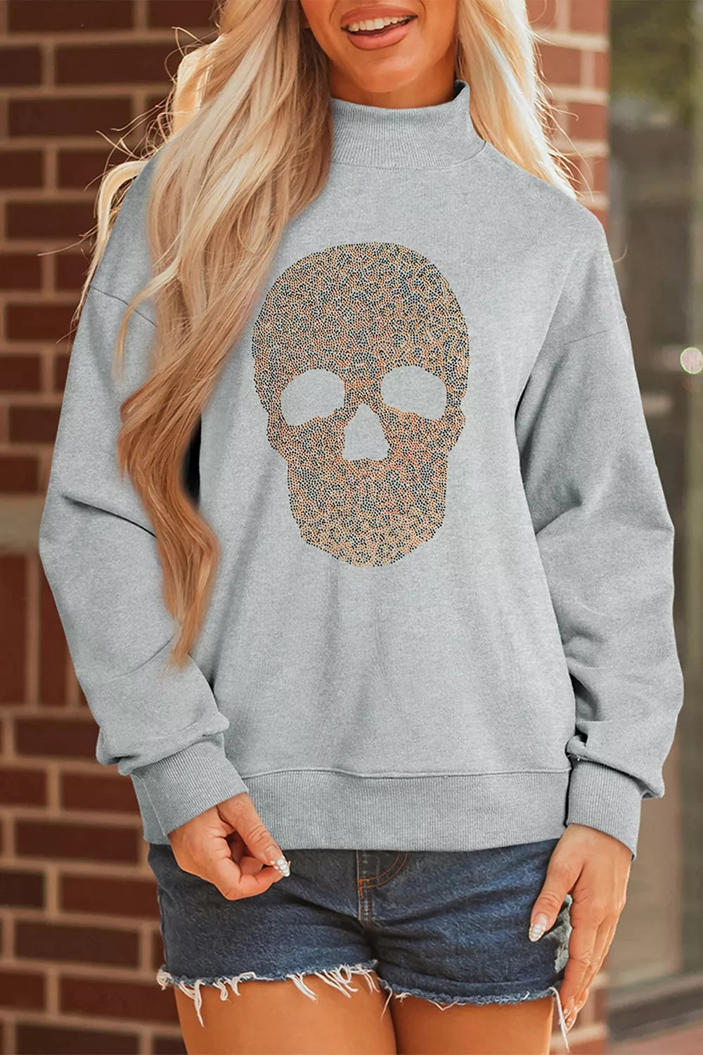 Gray mock-neck pullover sweatshirt with gold-toned skull graphic on the front