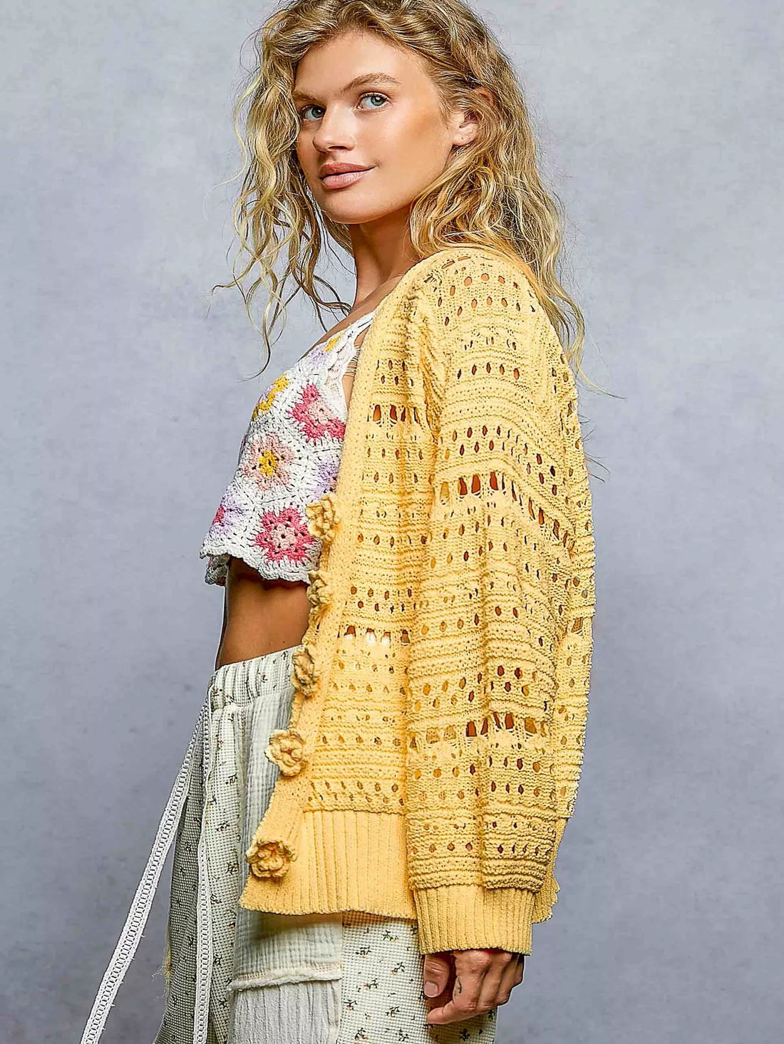 Yellow open-knit button cardigan from back view, long sleeves with ribbed waistband