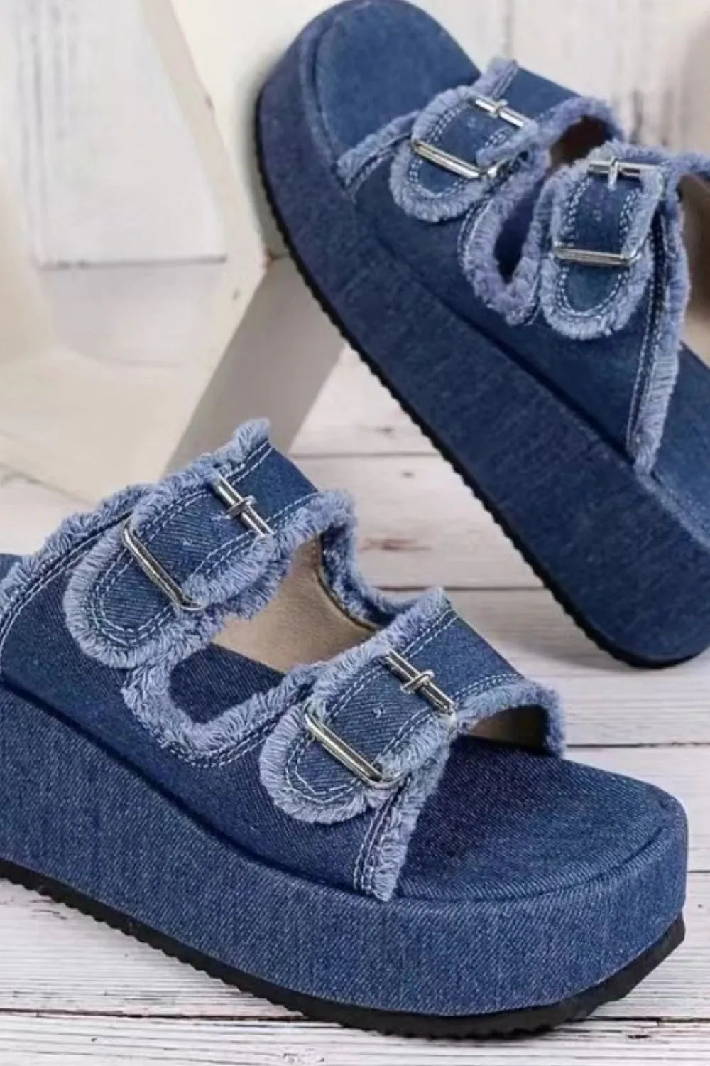 Blue denim wedge sandals with raw-edged dual straps and metal buckle details