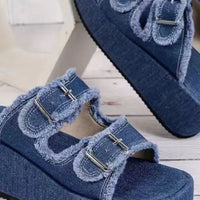 Blue denim wedge sandals with raw-edged dual straps and metal buckle details