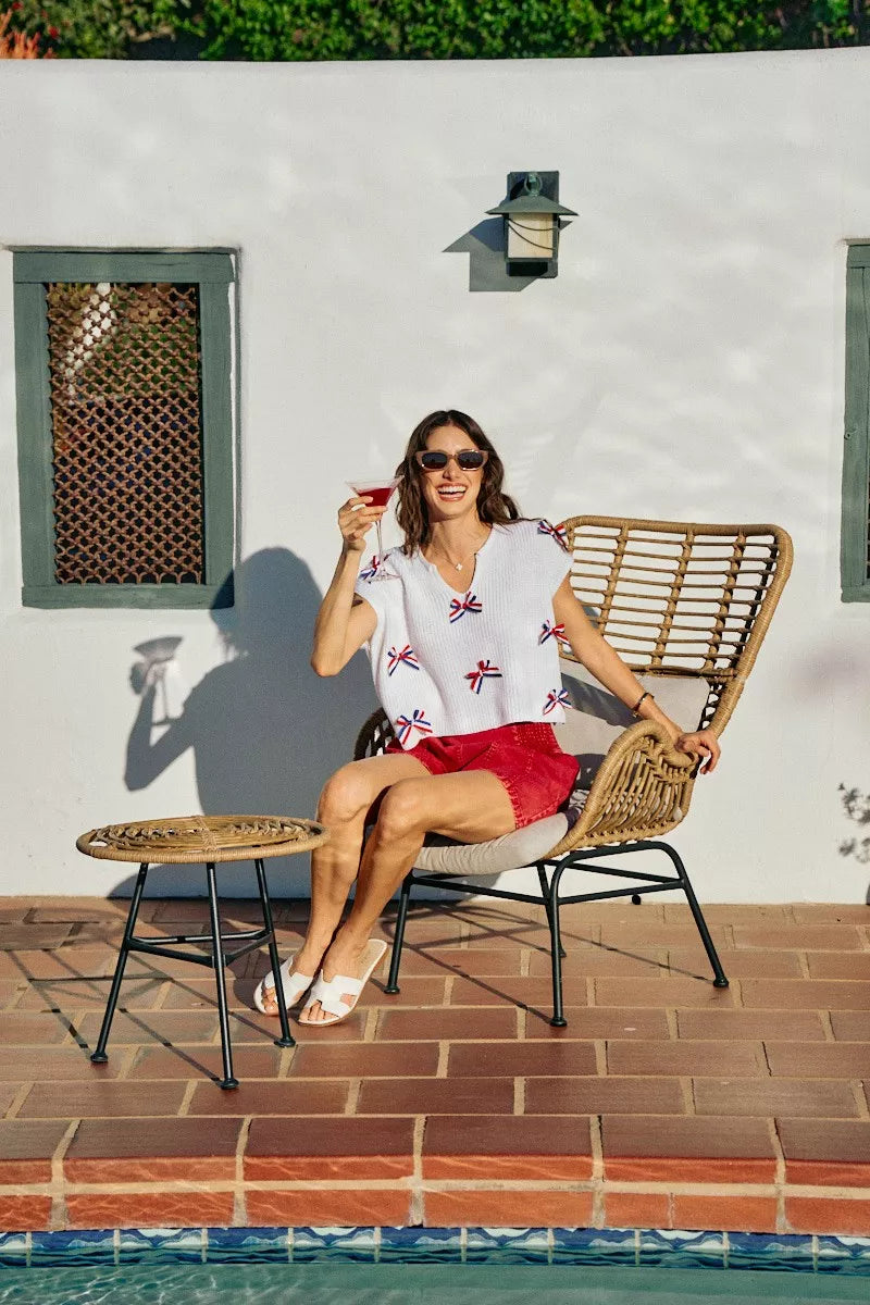 Off-white knit dolman sweater with red, white, and blue ribbon bows at neckline