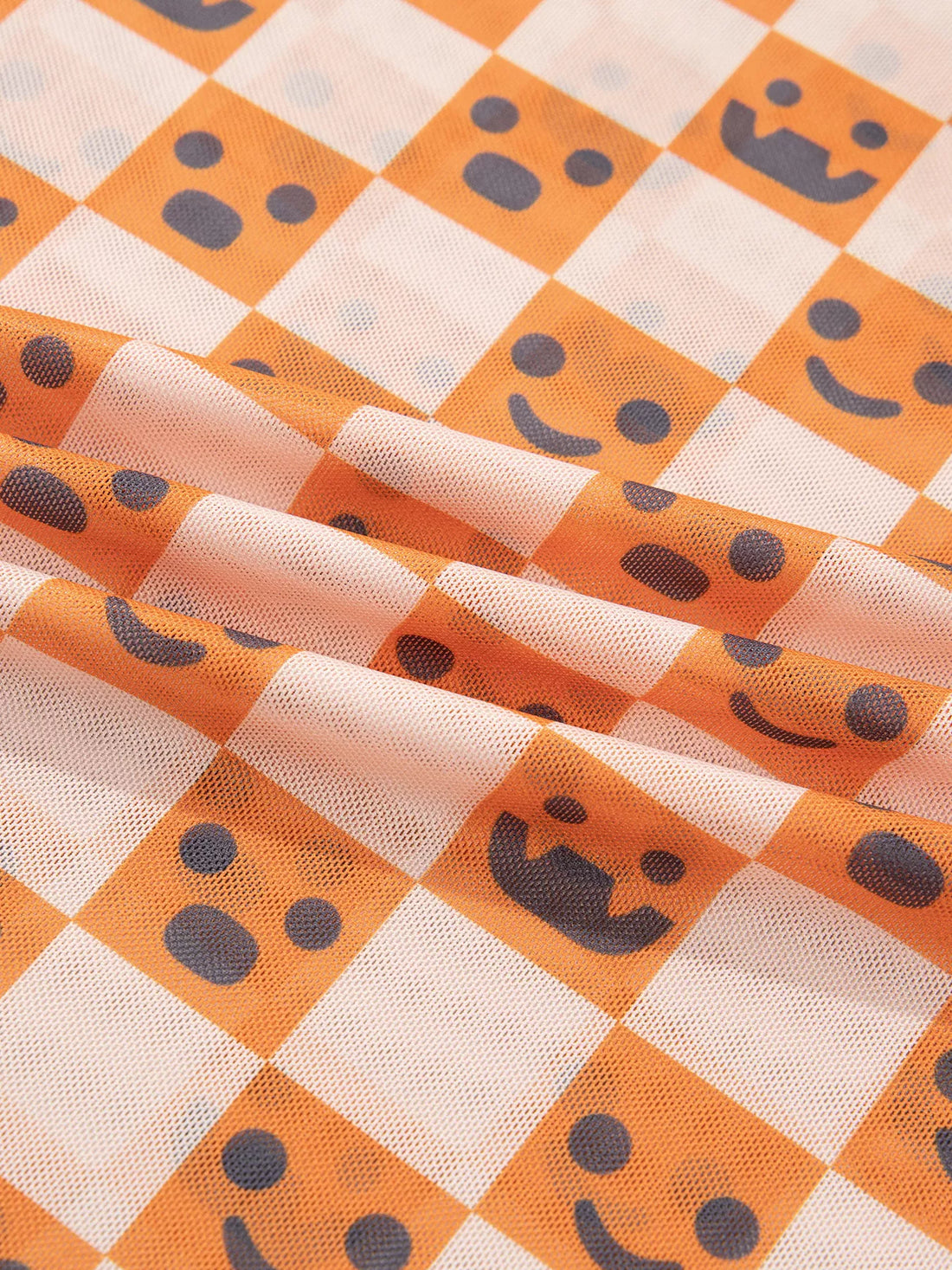 Close-up texture of orange-and-white checkered fabric with jack-o’-lantern faces