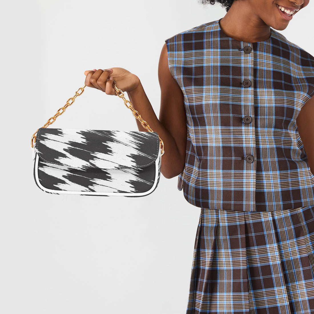 Small black and white patterned shoulder bag held by gold chain with white strap