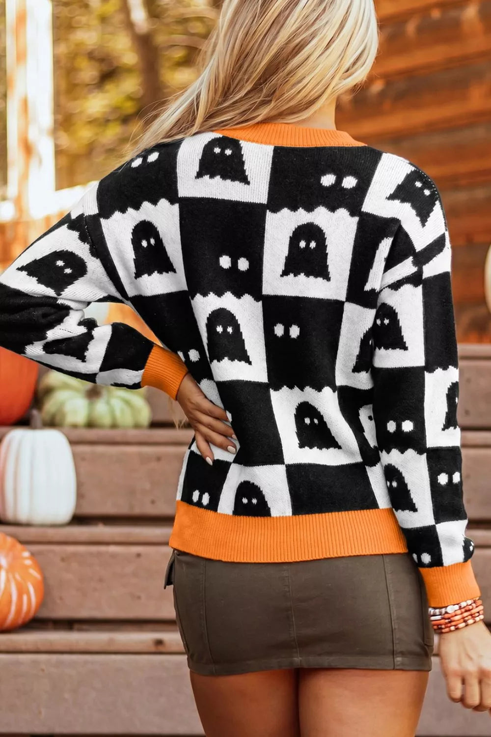 Side view of ghost checkerboard sweater in black and white with orange ribbed trim