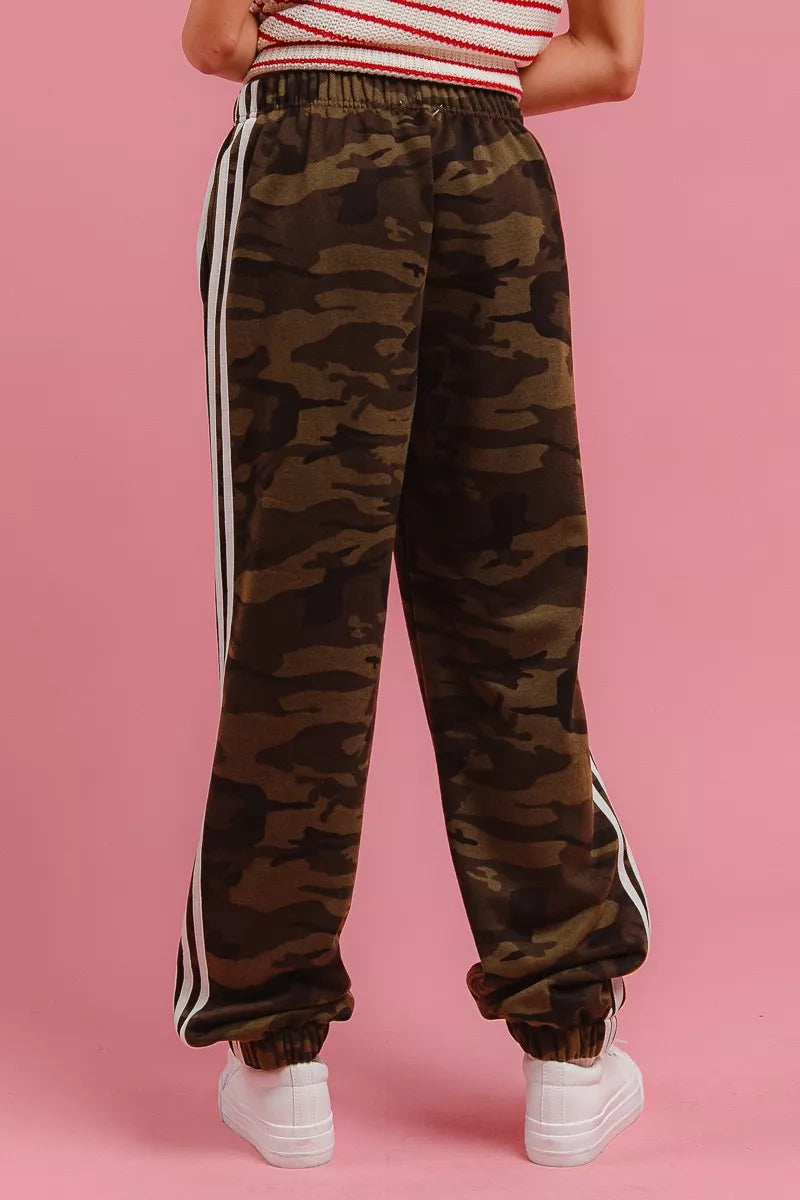 Camouflage track pants with elastic waistband, white side stripe, and cuffed hems.