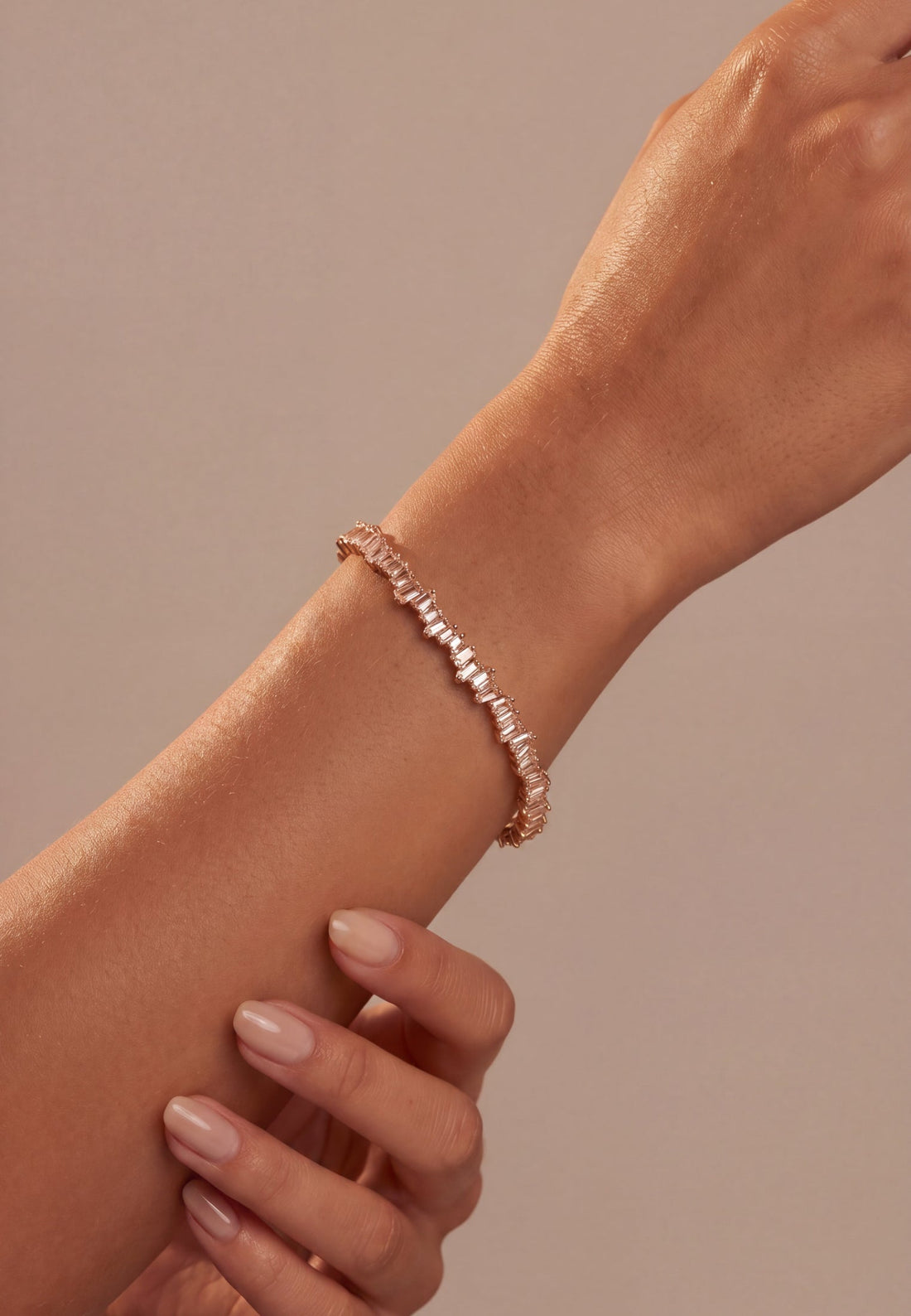 Rose gold ice cuff bangle with baguette-cut clear stones, close-up on wrist