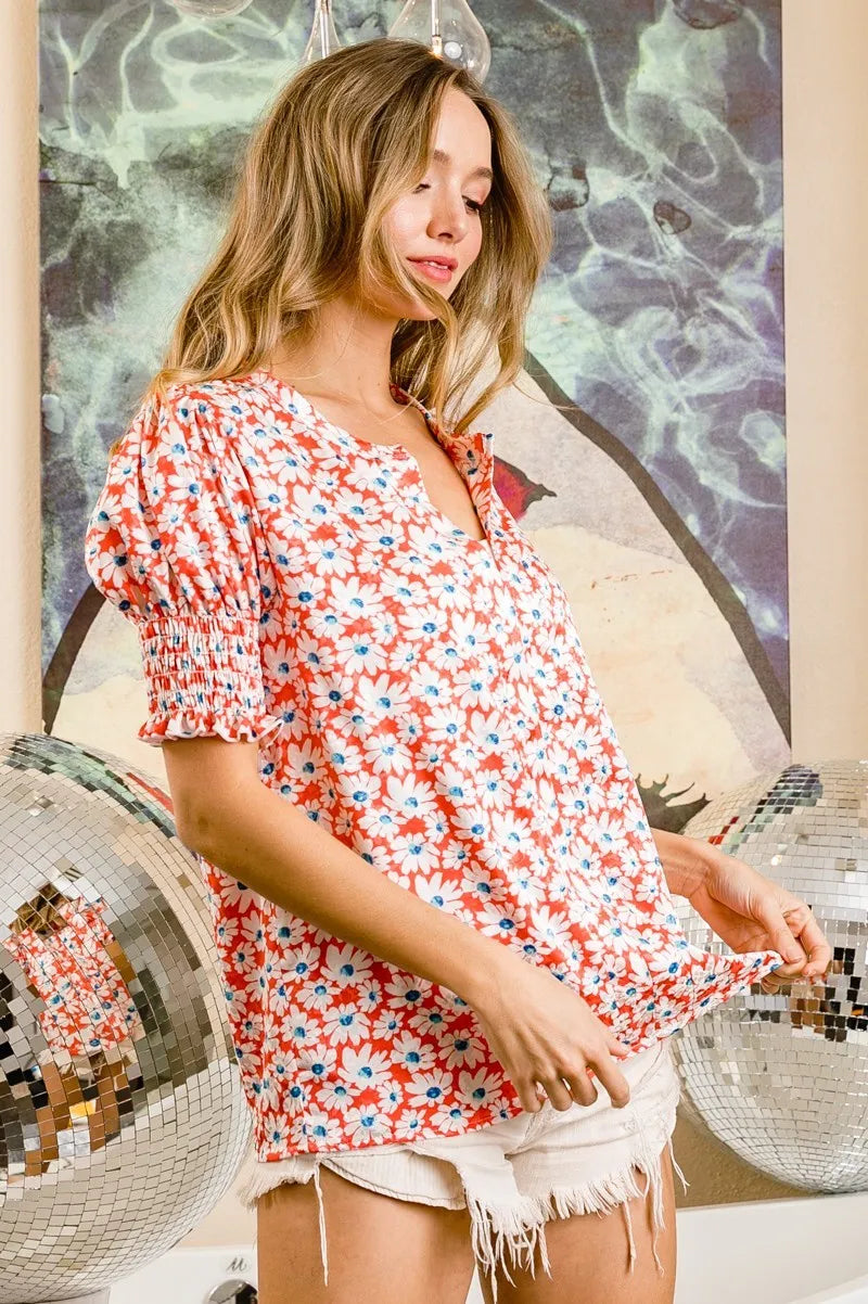 Orange floral V-neck top with smocked puff sleeves and short ruffled hem