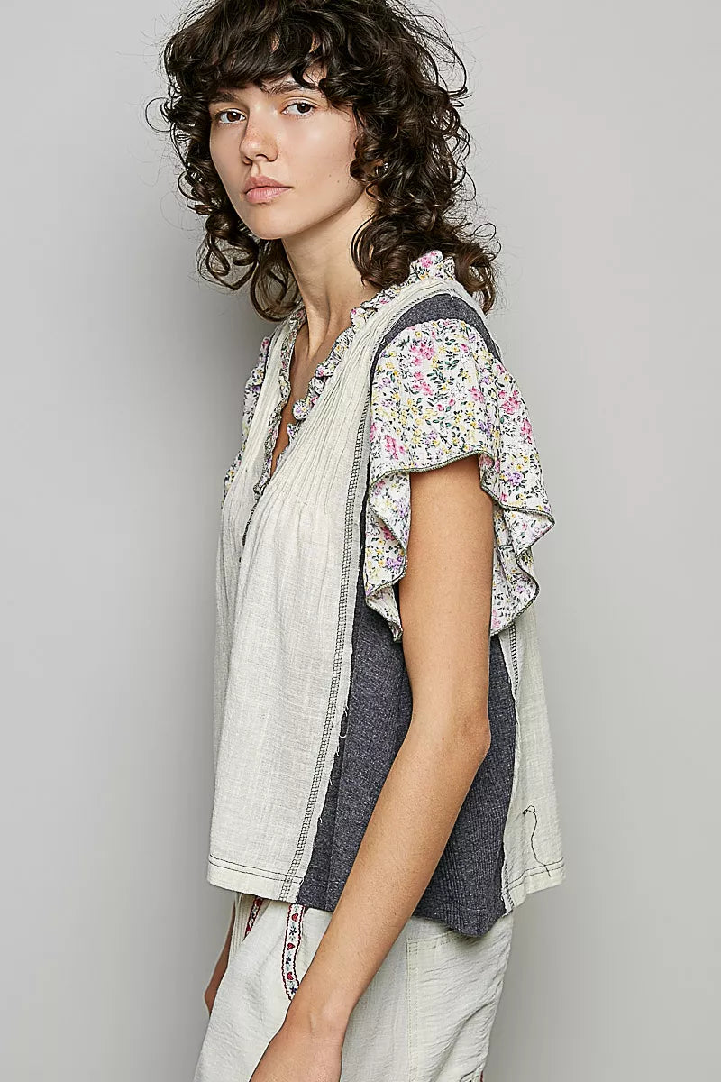 Cream V-neck blouse with floral ruffle sleeves and charcoal side panel detail
