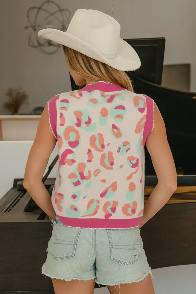 Back view of ivory sleeveless sweater vest with pink trim and leopard-style print.