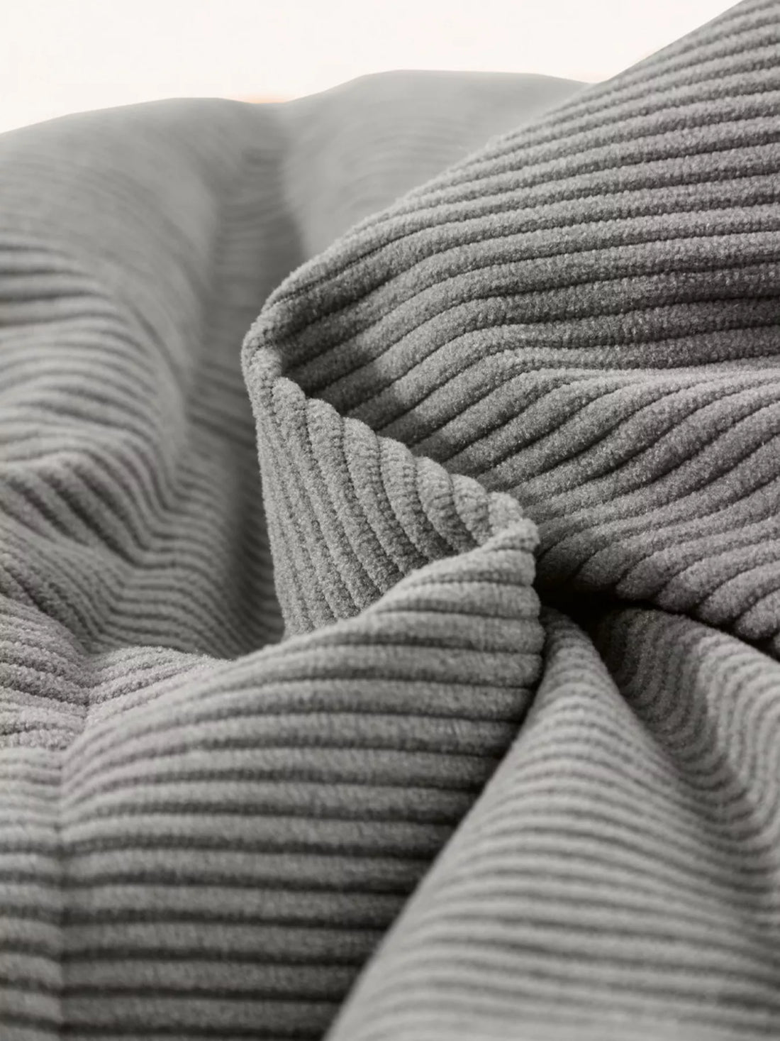 Gray corduroy puffer vest fabric close-up with ribbed texture and quilted padding layers.