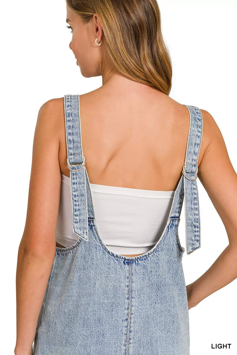 Back view of light wash denim overall dress with open-back neckline