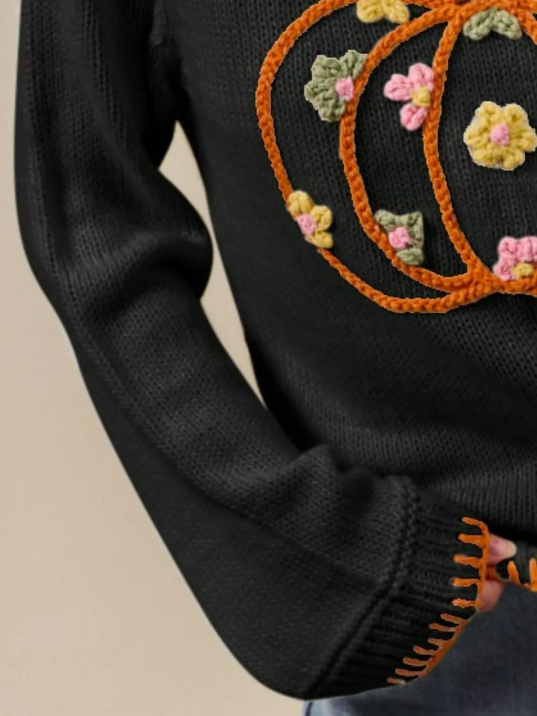 Black knit sweater sleeve with orange stitched trim and ribbed cuff