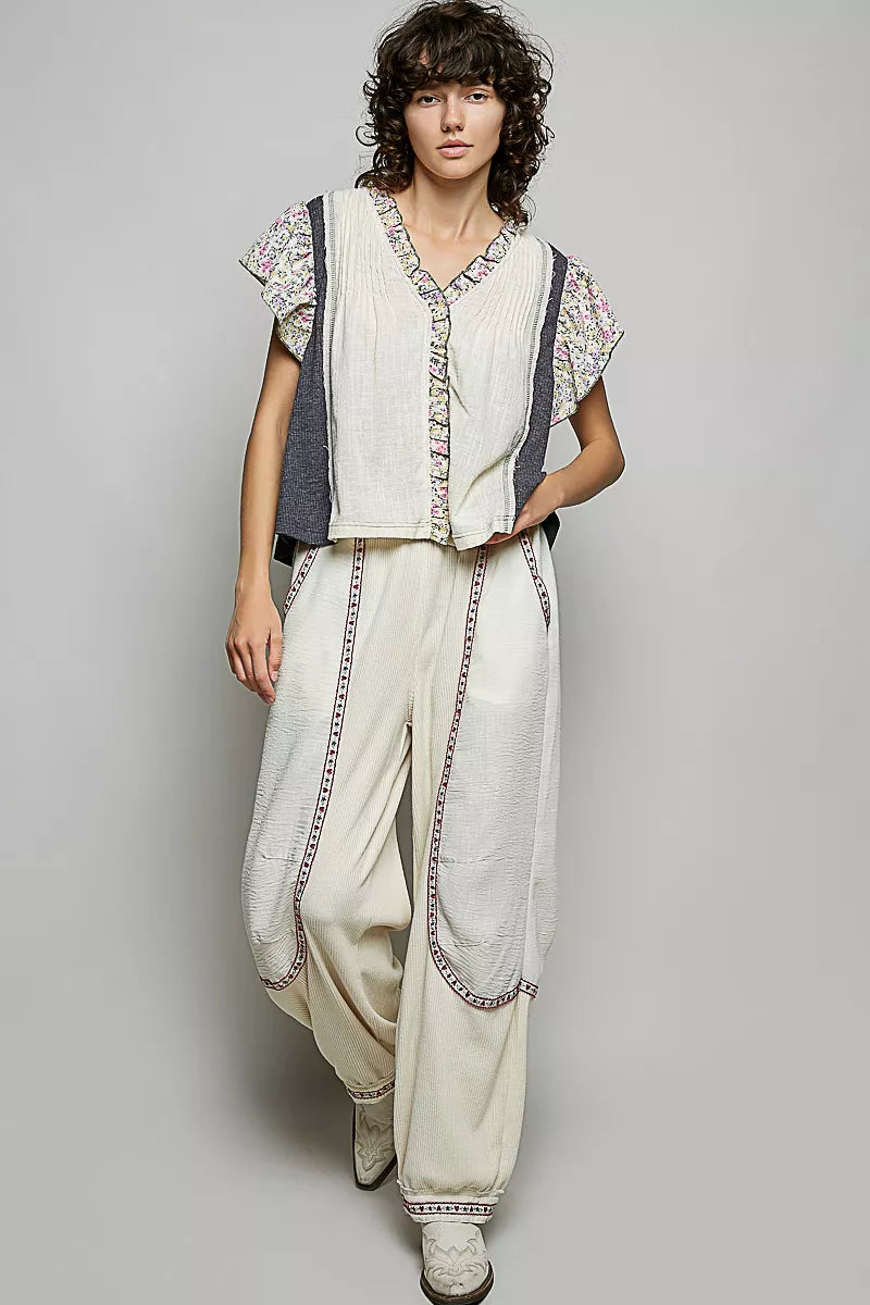 Cream V-neck blouse with floral ruffle sleeves and charcoal side panels, button front