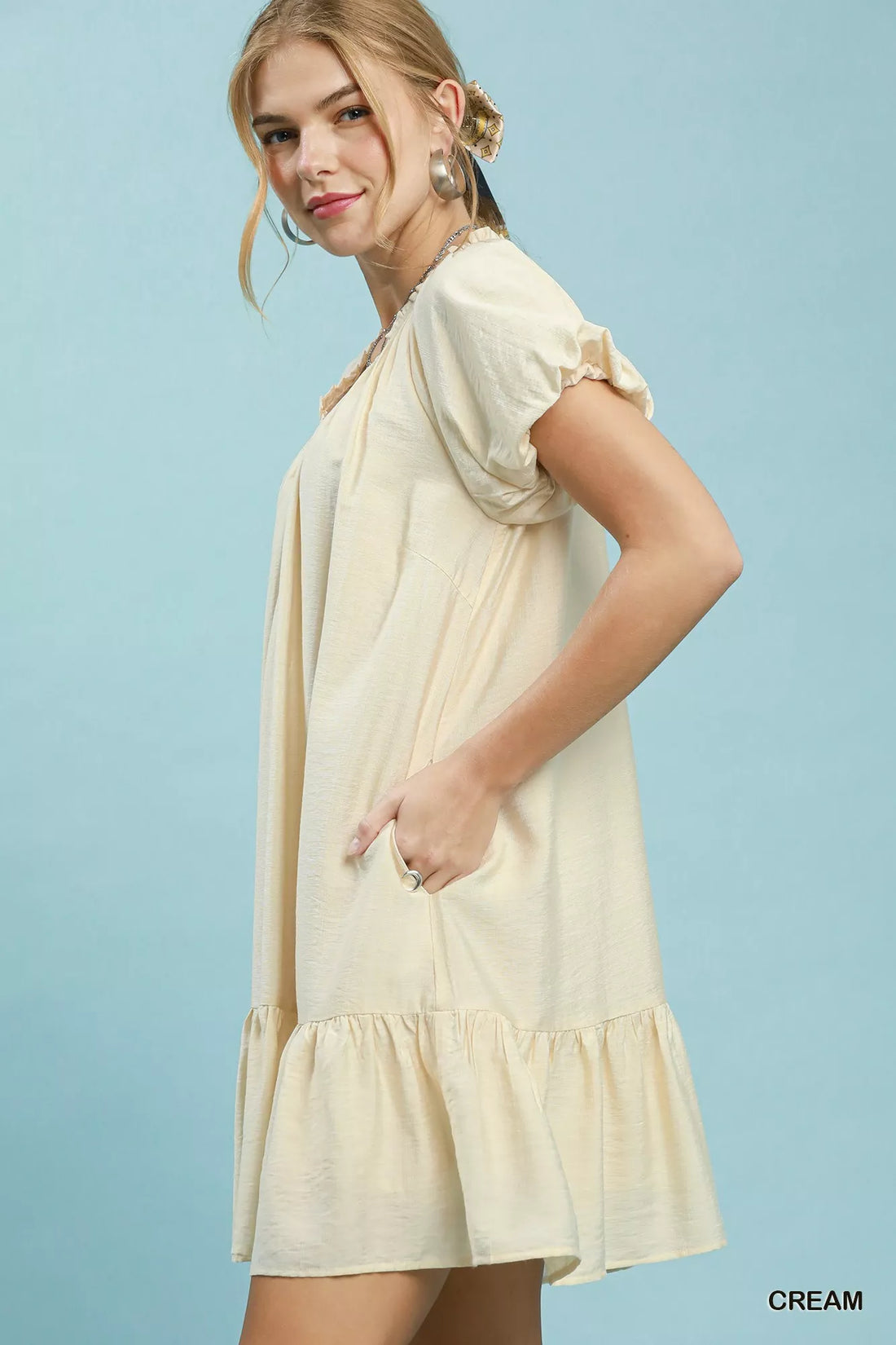 Cream shift mini dress with short puff sleeves and gathered ruffle hem detail.