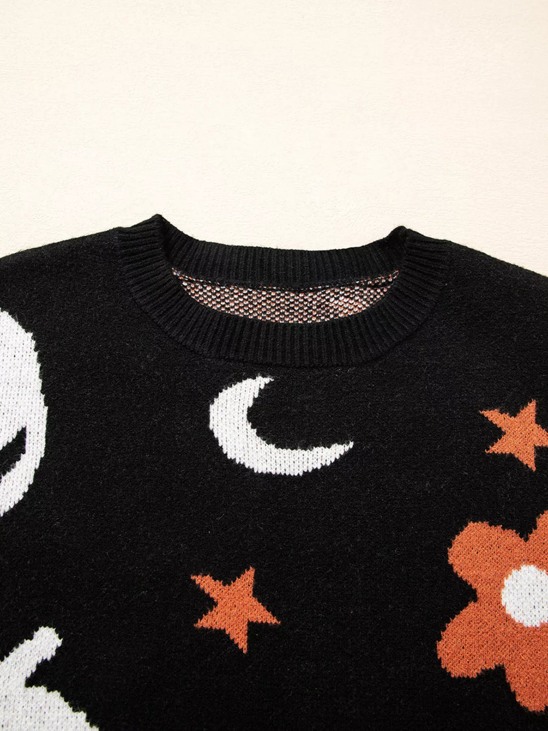 Black crewneck sweater close-up with moon and star knit pattern across the chest