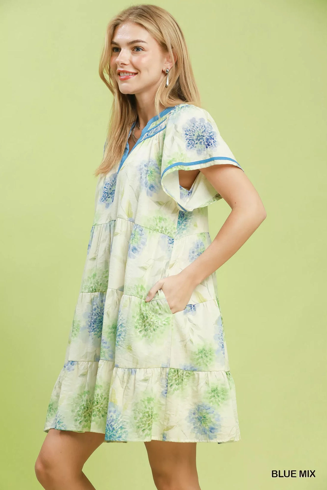 Floral babydoll dress angled view, blue contrast trim, tiered skirt on cream base