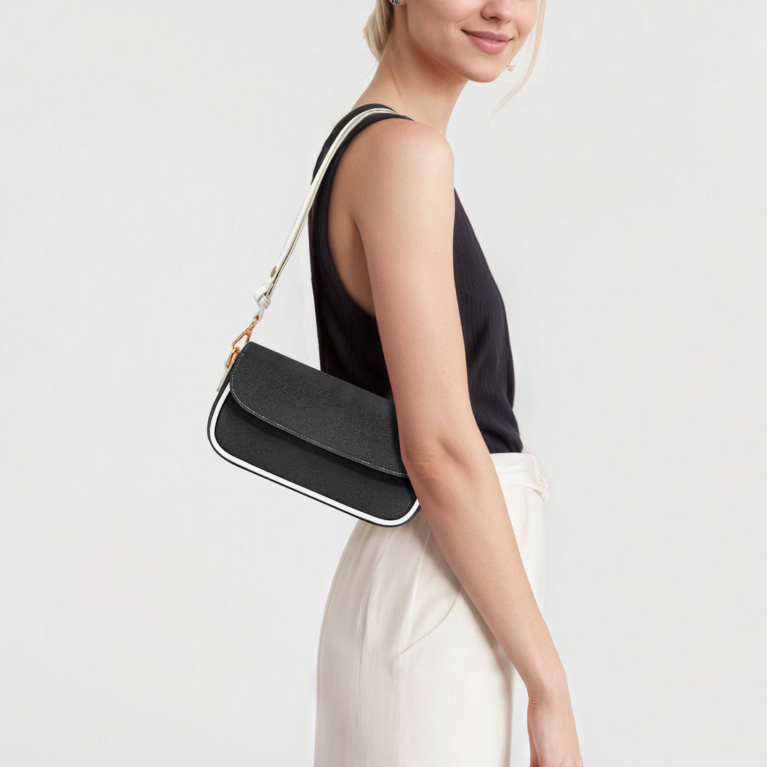 Black mini shoulder bag with flap and gold chain strap from side angle