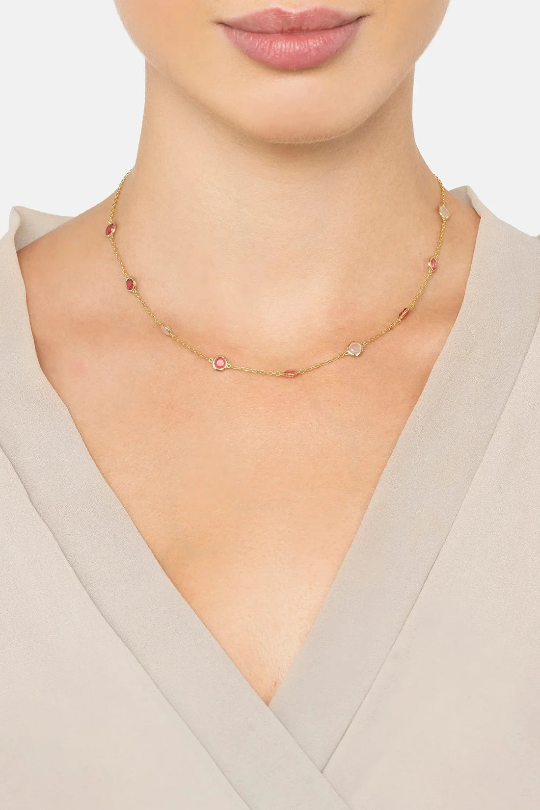 Gold bead charm necklace on model neck with pink and light blue accents