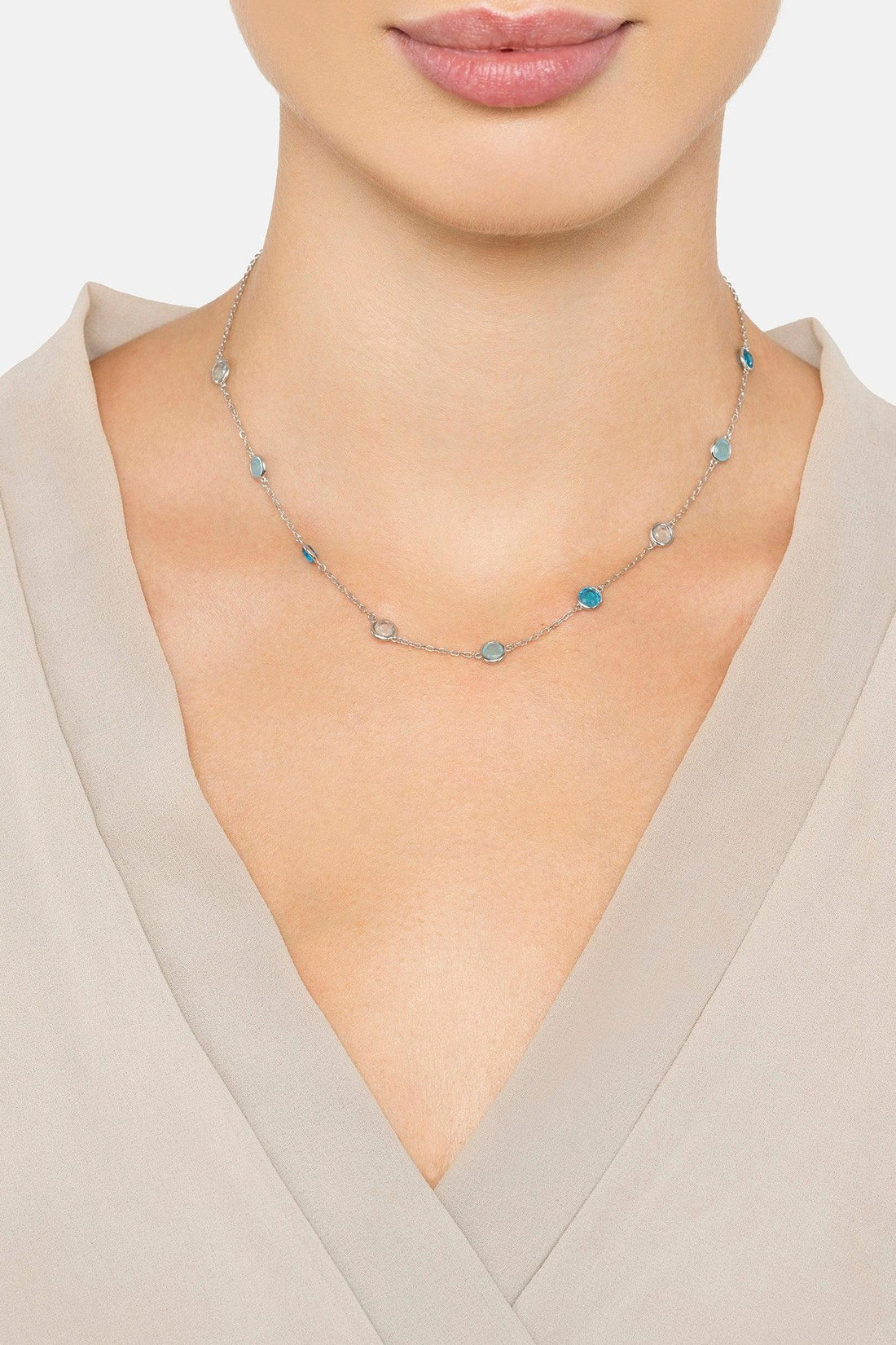Silver chain necklace with round blue beads, worn at the collarbone