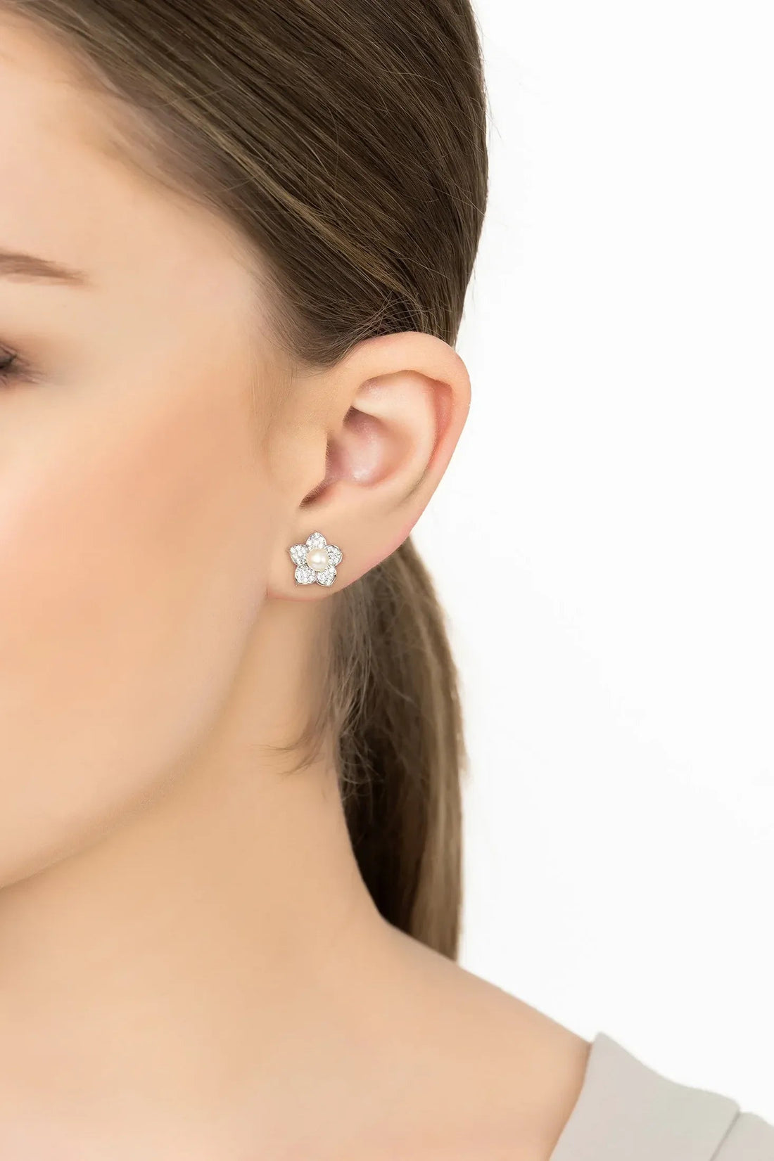 Silver-tone pearl stud earrings in flower design, worn on ear